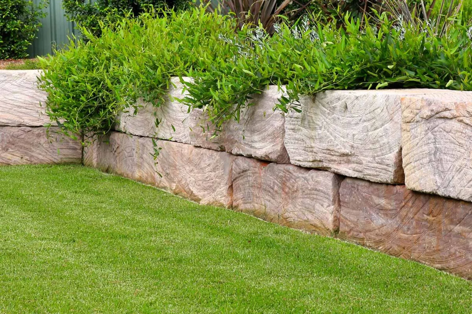 Tiered sandstone retaining wall along a lawn edge